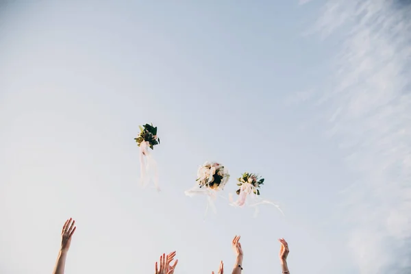 Novia y damas de honor lanzando ramos de bodas en el cielo en — Foto de Stock