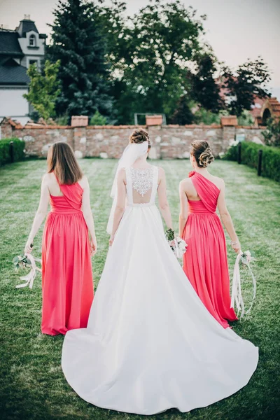 Gyönyörű menyasszony sétál koszorúslányok rózsaszín ruhák, gazdaság — Stock Fotó
