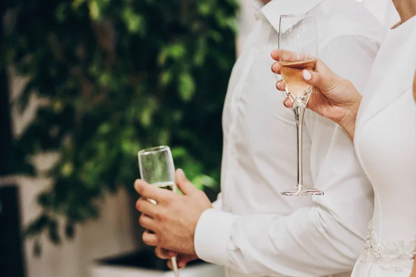 Stijlvol bruidspaar met champagne glazen en toasten op — Stockfoto