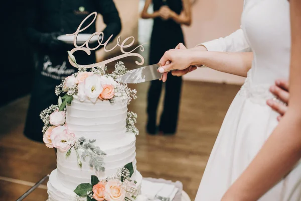 Brud- och brudgummen skär elegant bröllopstårta på bröllopsmottagningen — Stockfoto