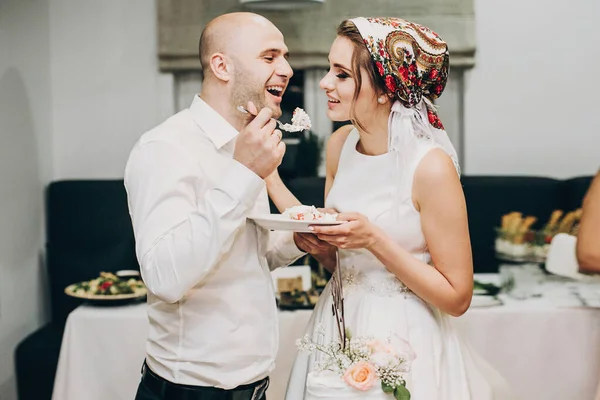 Novia y novio degustación elegante pastel de bodas en la recepción de la boda —  Fotos de Stock