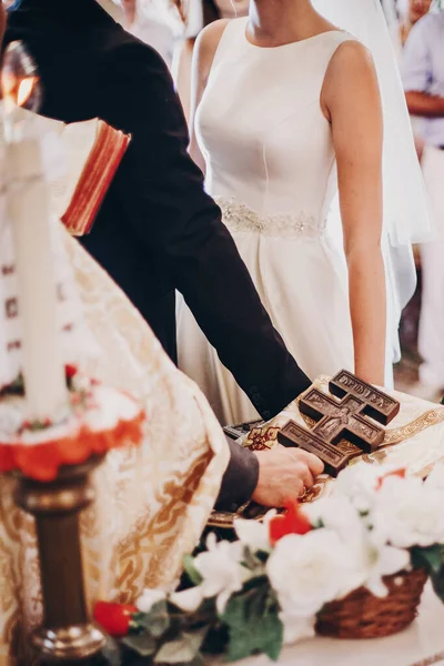 Svatební pár drží ruce na oltáři pod dřevěným křížem během — Stock fotografie
