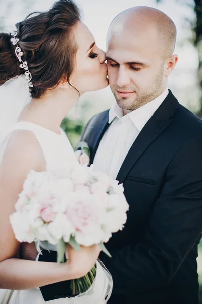 Κομψή νύφη και γαμπρός φιλιούνται απαλά στην ύπαιθρο. Όμορφη νύφη. — Φωτογραφία Αρχείου