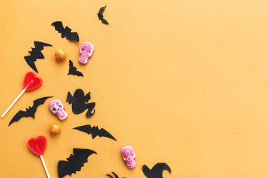 Cadılar Bayramı düz yatıyordu, kopya alanı. Cadılar Bayramı şeker, kafatasları, siyah yarasalar, hayalet, sarı arka plan üzerinde örümcek kağıt süslemeleri. Trick veya tedavi kavramı. Cadılar Bayramınız Kutlu Olsun