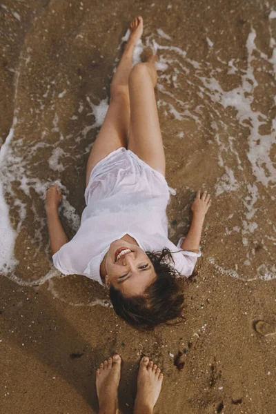Szczęśliwa Młoda Kobieta Mokrej Białej Koszuli Leżąca Plaży Rozbryzganych Falach — Zdjęcie stockowe