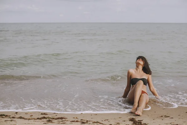 Счастливая Молодая Женщина Сидит Пляже Волнами Стильная Загорелая Девушка Современном — стоковое фото
