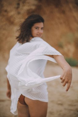 Farkındalık ve rahatlama. Plajda yürüyen beyaz yazlık elbiseli neşeli kız. Elbiseli eller yakın plan. Kaygısız genç kadın deniz kıyısında dinleniyor. Yaz tatili.