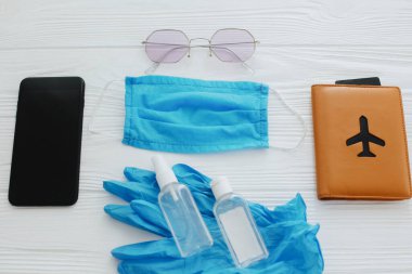 2020 yazında iyi yolculuklar. Mavi maske, eldivenler, antiseptik ve dezenfektan, pasaport, güneş gözlüğü ve telefon beyaz arka planda. Coronavirus tatil koruma tedbirleri