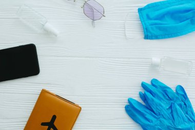 Mavi maske, eldivenler, antiseptik ve dezenfektan, pasaport, güneş gözlüğü ve telefon beyaz arka planda, kopyalama alanı. 2020 yazında iyi yolculuklar. Coronavirus tatil koruma tedbirleri