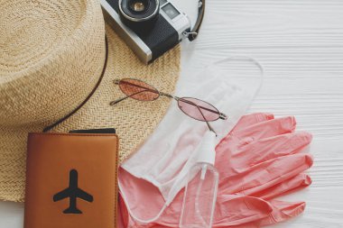 2020 yazında. Yüz maskesi, pembe eldivenler, antiseptik ve dezenfektan, pasaport, güneş gözlüğü, beyaz arka planda hasır şapka. Güvenli seyahat ve Coronavirus tatil koruma tedbirleri