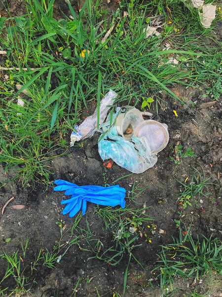 Disposable medical gloves on ground with single use plastic trash. How to dispose used medical gloves right after coronavirus pandemic. Do not throw them away