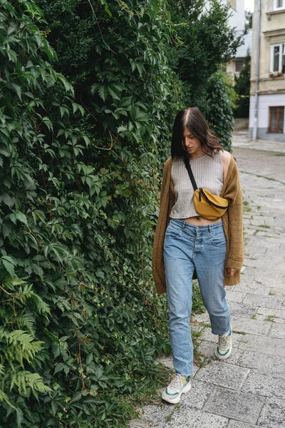 Молодая Женщина Непринужденной Модной Одежде Прогуливается Зеленой Кустарниковой Стене Городской — стоковое фото