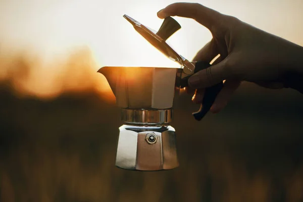 在乡村草本植物中 旅行者拿着Geyser咖啡壶 带着新鲜咖啡 沐浴在阳光下 大气中的乡村时刻 旅行中的替代咖啡酿造 — 图库照片