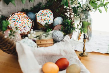 Paskalya yumurtaları, paskalya ekmeği, jambon, pancar, tereyağı, yeşil tahta dallarla süslenmiş köy sepetinde sosisler ve mumla süslenmiş çiçekler. Geleneksel Paskalya sepeti.