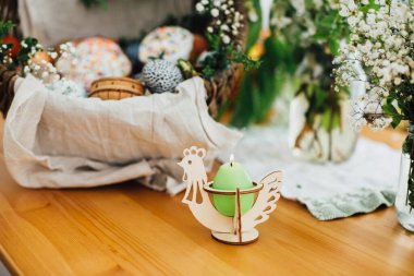 Geleneksel Paskalya sepetinin arka planında kilisedeki dualar için mum. Paskalya yumurtası, pasta, jambon, pancar, yeşil buxus dallarıyla süslenmiş köy sepetinde tereyağı.