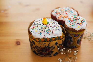 Ev yapımı paskalya pastaları. Kırsal ahşap masa üzerinde beyaz çiçeklerle birlikte renkli serpiştirilmiş. Mutlu Paskalyalar. Geleneksel Paskalya ekmeği. Boşluğu kopyala