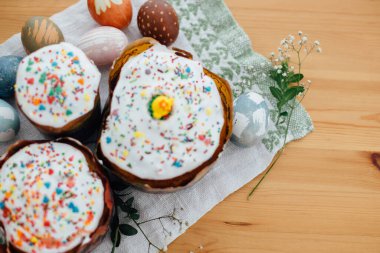 Şık paskalya yumurtaları doğal boyanmış ve ev yapımı paskalya pastası kır bezinde çiçekler ve ahşap masada yeşil brunchlar. Mutlu Paskalyalar. Geleneksel Paskalya yemeği. Düz yatıyordu