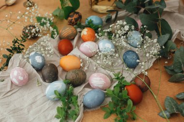 Kırsal arka planda çiçeklerle doğal boya ile boyanmış modern paskalya yumurtaları. Sıfır ziyan tatili Ahşap masada bahar çiçekleri ve yeşil dallarla süslü Paskalya yumurtaları.