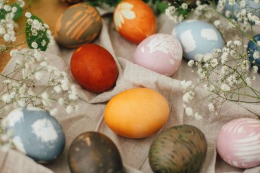 Kırsal arka planda çiçeklerle doğal boya ile boyanmış modern paskalya yumurtaları. Sıfır ziyan tatili Ahşap masada bahar çiçekleri ve yeşil dallarla süslü Paskalya yumurtaları.