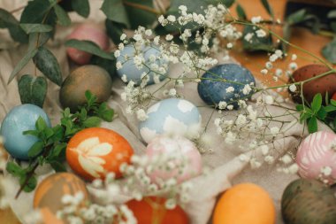 Kırsal arka planda çiçeklerle doğal boya ile boyanmış modern paskalya yumurtaları. Sıfır ziyan tatili Ahşap masada bahar çiçekleri ve yeşil dallarla süslü Paskalya yumurtaları.