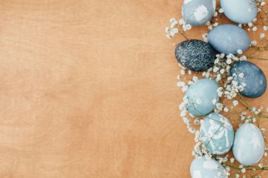 Mutlu Paskalya tebrik kartları. Çiçekler ve modern Paskalya yumurtaları kırsal ahşap arka planda yatar, kopyalama alanı. Şık pastel mavi Paskalya yumurtaları kırmızı lahanadan doğal boyayla boyanmış..