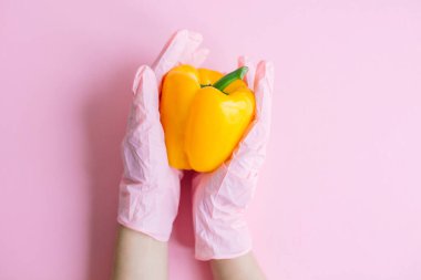 Pembe arka planda sarı biber tutan pembe eldiven. Karantinada güvenli alışveriş. İnternetten yemek sipariş et ve evde kal. Virüs salgınını önlemek için. Kendine dikkat et.