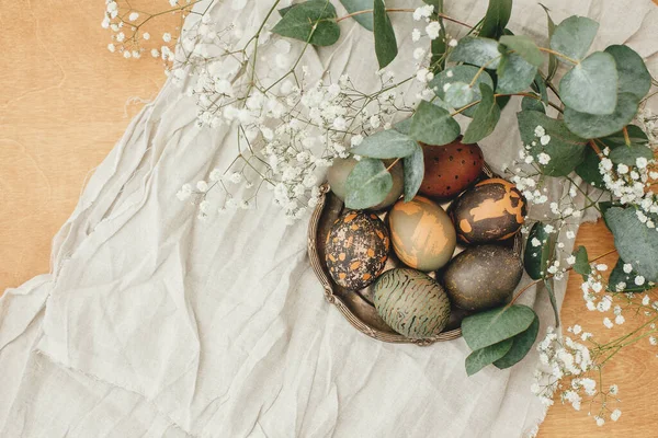 复活节快乐公寓躺在地上 现代复活节彩蛋与春天的花朵和桉树在乡村木桌上 色彩艳丽的灰色石子和绿色复活节彩蛋 用红茶染色制成 — 图库照片