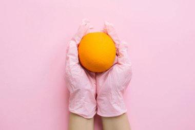 Pembe eldivenli eller pembe arka planda turuncuyu düz tutuyordu. Yiyecek sipariş et ve karantina sırasında güvenli bir şekilde teslim et. Evde kal. Kendine dikkat et. Virüs salgınını önlemek için. Temiz yemek.