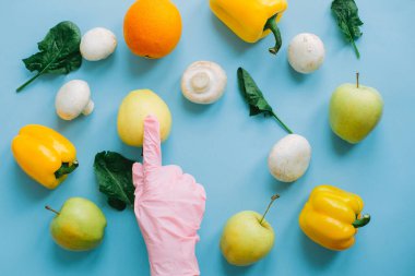 Taze organik yiyecek sipariş et ve onları güvenli bir şekilde evine götür. Mavi arka planda sebzeli ve meyveli sebzeli sebzeleri toplayarak pembe eldiveni getir. Evde kal. Dikkatli ol..