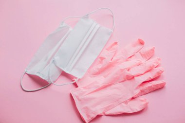 Pembe eldivenler, pembe arka planda yüz maskesi. Koronavirüs salgını. Kendine dikkat et. Virüs salgınını önlemek için. Güvenli alışveriş ve karantinada yürümek. Evde güvenli bir hayat sür.
