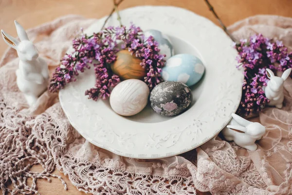 Stilvolle Ostereier Auf Vintage Teller Weiße Hasen Und Fliederfarbene Blumen — Stockfoto