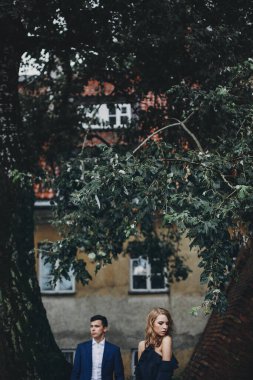 Avrupa caddesinde yeşil ağaçların altında kucaklaşan şık bir çift. Hassas romantik an. Modaya uygun bir erkek ve kadın birbirlerine nazikçe poz veriyorlar. Sevgililer Günü