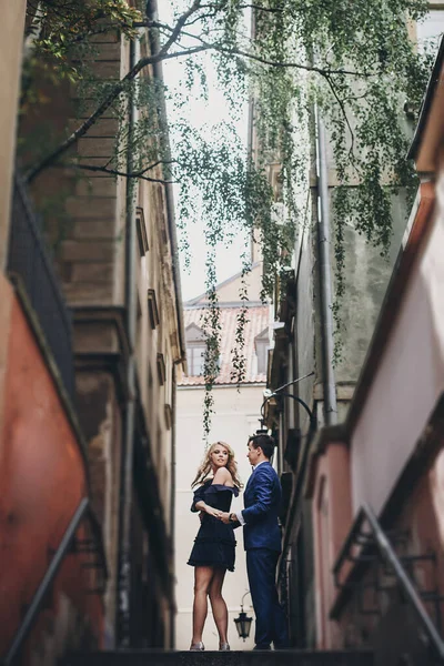 スタイリッシュなカップルは 古い建築を背景にヨーロッパの街の通りで一緒に受け入れます 都会で一日を楽しむのが好きなおしゃれな男女 ヨーロッパを旅する — ストック写真