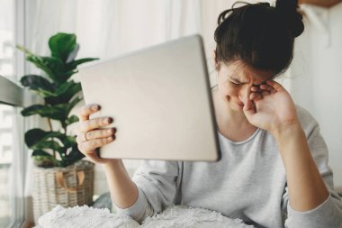 Karantina sırasında evde otururken tabletten gelen kötü haberlerle ağlayan üzgün kız. Genç bir kadın işini ve depresyonunu kaybetmekten endişeleniyor. İşsizlik ve ekonomik kriz. Mali istikrarsızlık