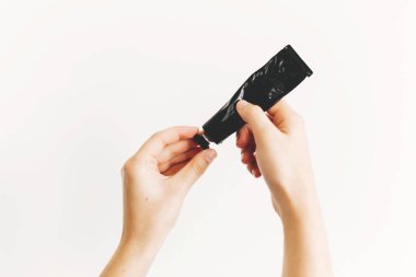 Dezenfektan ve alkol jeli kullandıktan sonra deriyi nemlendirmek için siyah tüpte krem tutan eller. Kuru cilt tedavisi. Lüks cilt bakımı. El kremi