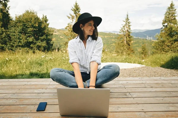 Gadis Hipster Menggunakan Laptop Duduk Teras Kayu Dengan Pemandangan Indah — Stok Foto