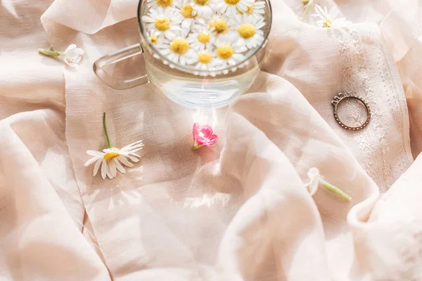 Vildblommor Bakgrunden Mjuk Beige Tyg Med Tusensköna Blommor Vatten Glas — Stockfoto
