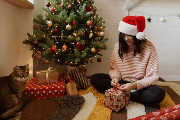 Stylish Young Woman Wrapping Christmas Present Paper Christmas Tree Lights — Stock Photo, Image