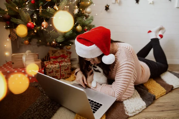 Genç Bir Kadın Halıda Kedi Dizüstü Bilgisayarla Oturmuş Hediyelerle Noel — Stok fotoğraf
