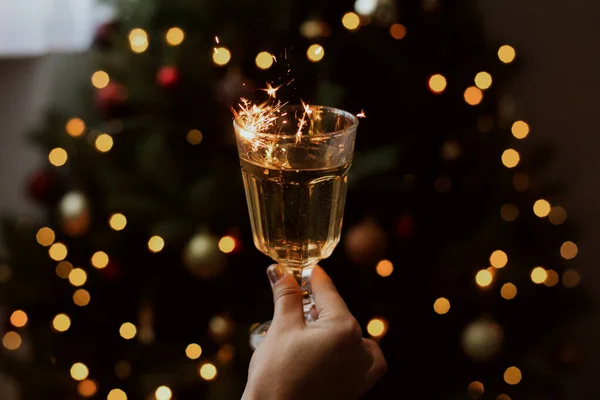 장소에 황금색 보케등을 배경으로 샴페인 피웁니다 크리스마스 트리에서 스파클러랑 손으로 — 스톡 사진