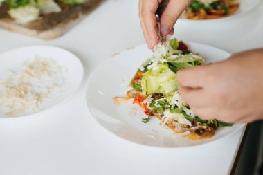 Eller, modern mutfakta ev yapımı pizzaya parmesan dilimi koyuyor. Mantarlı, domatesli, roka ve peynirli lezzetli pizza. Ev yemeği konsepti