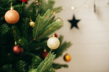 Noel ağacında fotokopi alanı olan modern altın takılar. Noel ağacına parlak parıltılı süsler asmak, İskandinav odasının şenlikli dekorasyonu. İyi tatiller.