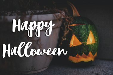 Mutlu Cadılar Bayramı tebrik kartları. El yazısıyla Mutlu Cadılar Bayramı metni, balkabağı kabağı Jack-o-Lantern 'in arka planında, parlayan yüzüyle ve mumuyla.
