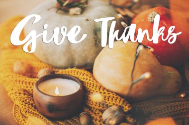 Şükran Günü tebrik kartın kutlu olsun. El yazısıyla balkabağı, sonbahar yaprakları, mum, sarı örülmüş süveterin üzerindeki sıcak ışıklar hakkında teşekkür mesajı. Seçici odak