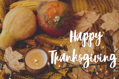 Şükran Günü tebrik kartın kutlu olsun. Balkabaklarının, sonbahar yapraklarının, mumların, sarı örülmüş süveterin üzerindeki sıcak ışıkların üzerine el yazısıyla Mutlu Şükran Günü mesajı. Seçici odak