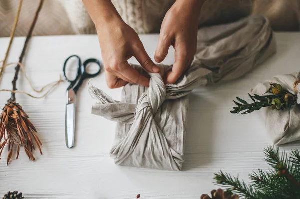 Tangan Membungkus Hadiah Natal Dalam Kain Linen Dalam Gaya Furoshiki — Stok Foto