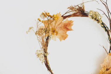 Beyaz duvarda el yapımı sonbahar çelengi. Sonbahar yaprakları, dallar ve çiçeklerden yapılmış kırsal mevsimlik çelenkler. Merhaba sonbahar ve Şükran Günü dekorasyonunuz kutlu olsun.