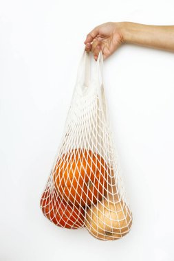 Eko dostu sonbahar tatili. Beyaz arka planda balkabağı olan tekrar kullanılabilir alışveriş torbası tutan bir kadın. Sonbahar hasatı