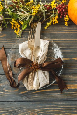 Çevre dostu Şükran Günü yemeği. Çatal bıçak takımı, sonbahar süslemeleri, balkabağı, doğal dallar ve kır masasında sonbahar çiçekleri olan şık bir tabak. Sonbahar düğün sofrası