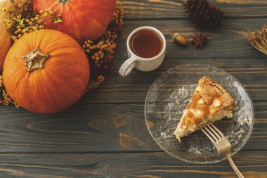 Elmalı turta dilimi cam tabakta çay kabaklı, güz çiçekli ve çam kozalaklı. Elmalı ev yapımı Charlotte, basit bir tarif.